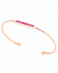 Rose gold bangle with pink gemstones on a white background