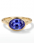 Gold ring with a blue gemstone on a white background