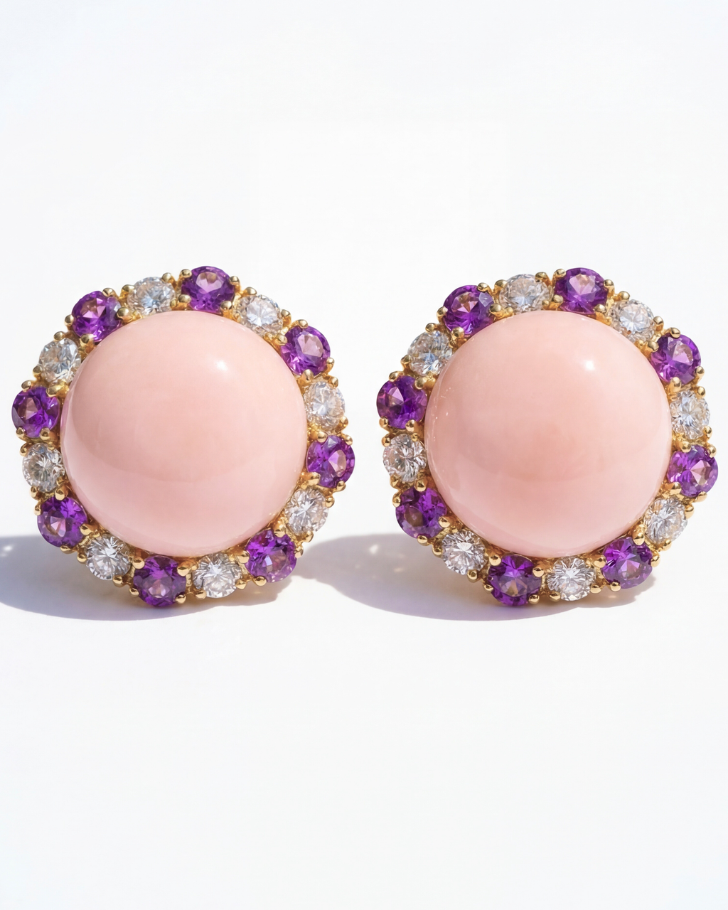 Pair of earrings with pink center stones and purple and clear gemstone accents on a white background