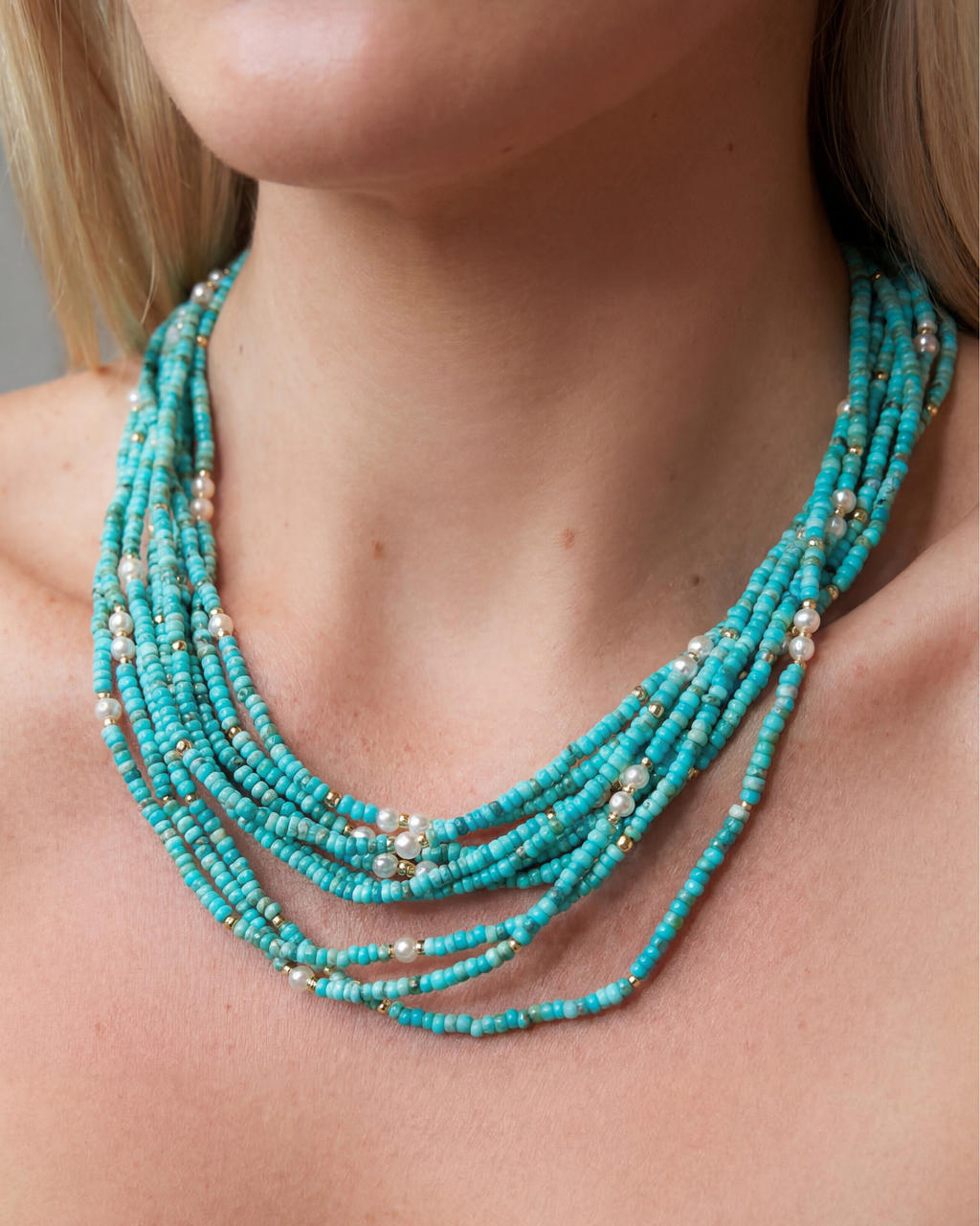 Turquoise beaded necklace worn by a person with a neutral background